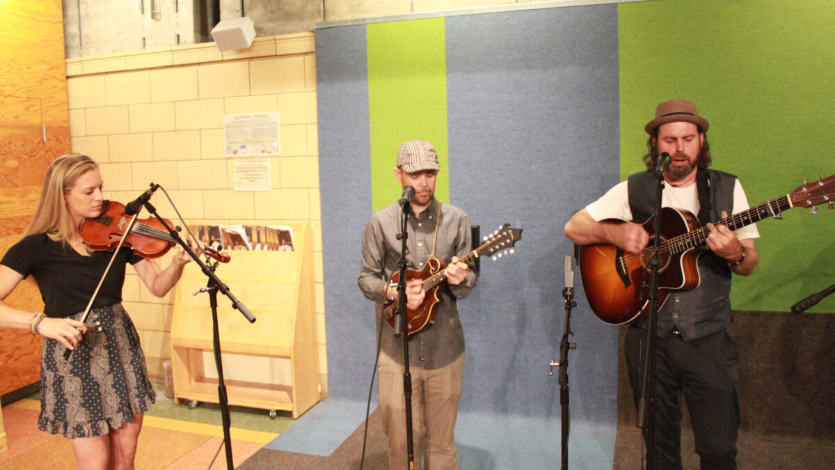 Three adult musicians performing on fiddle, mandolin, and guitar