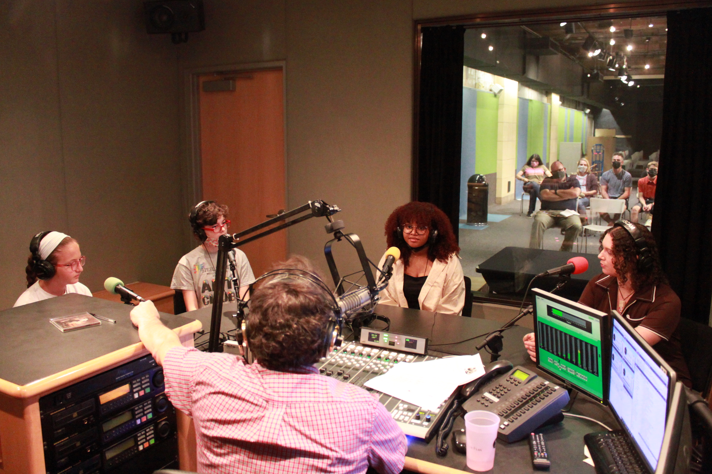 Four teens wearing headphones being interviewed in a radio studio