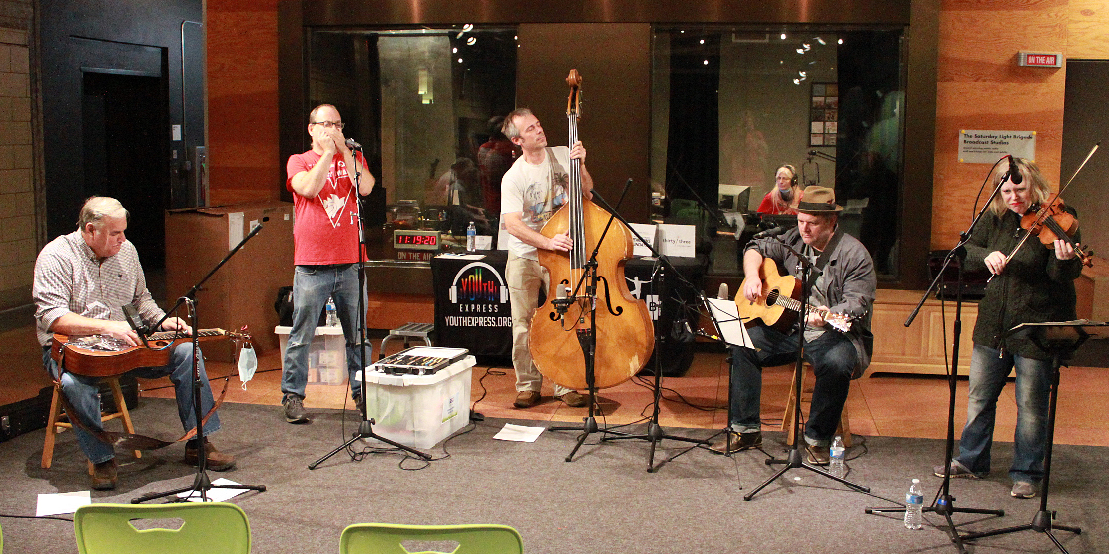 Five adult musicians performing on dobro, harmonica, upright bass, guitar, and violin