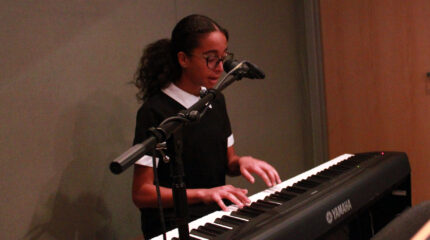 Youth playing piano and singing into a microphone in a radio studio