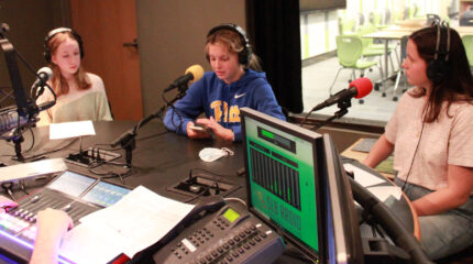 Three youth wearing headphones being interviewed in a radio studio