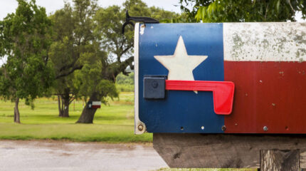 A mailbox with the colors and design of the Texas state flag: a white rectangle on top of a red rectangle, both to the right of a blue square with a white star in the center