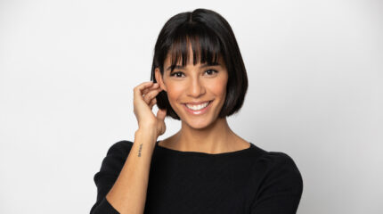 Adult with a black bob hair cut and a black top smiling in profile