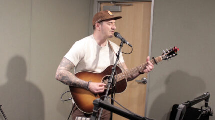 Adult playing acoustic guitar and singing