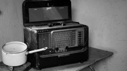 Old radio on a card table next to a small white cooking pot