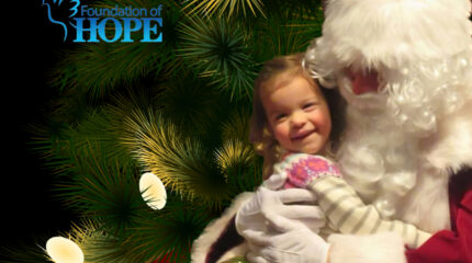 A graphic of Santa Claus holding a child in front of a Christmas tree with lights on it, and a graphic of a light blue dove and the text "Foundation of Hope" in light blue