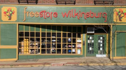A green storefront with yellow accents, with the text "free" in yellow and "store wilkinsburgh" in red above the doors