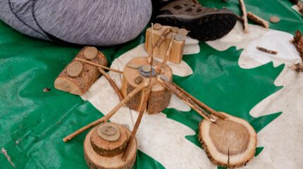 A contraption made out of pebbles, sticks and small log stumps on a green and white tarp