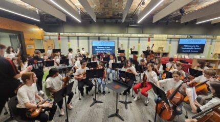 A large group of youth wearing white shirts in an orchestra