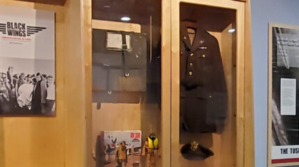 A military uniform and other military paraphernalia displayed in a glass case