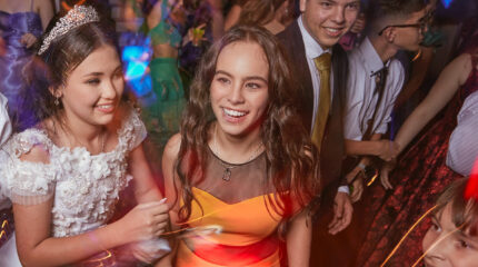 A group of teens wearing formal attire smiling and dancing