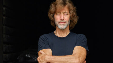 An adult posing in profile with their arms folded
