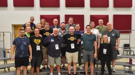 A group of adults smiling and standing in profile on a set of bleachers