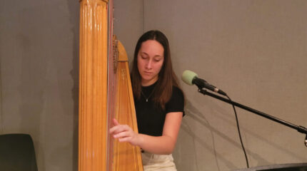 A teen playing harp in a radio studio