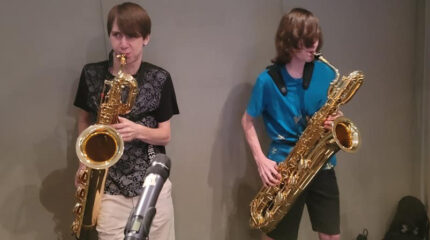 Two youth playing baritone saxophones in a radio studio