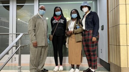 Two teens and two adults, all wearing face masks and standing in profile