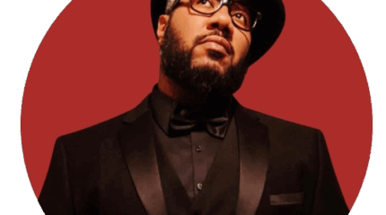 A adult wearing a black suit and a top hat posing in a red circle on a white background