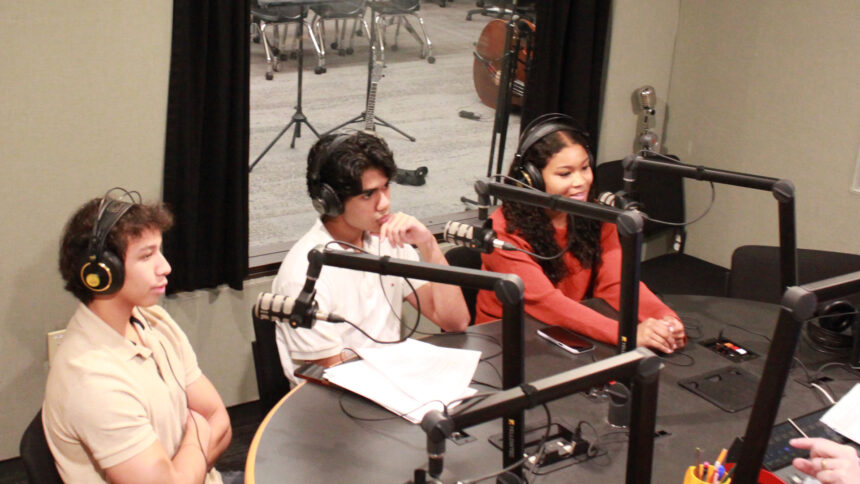 Three teens wearing headphones speaking into microphones being interviewed in a radio studio