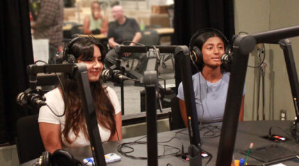 two teens sitting at a radio studio desk