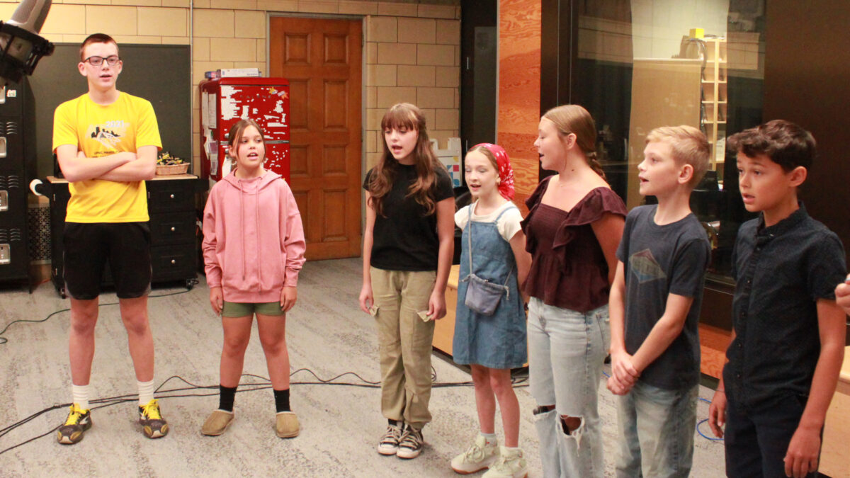 Seven youth singing in a choir into a microphone