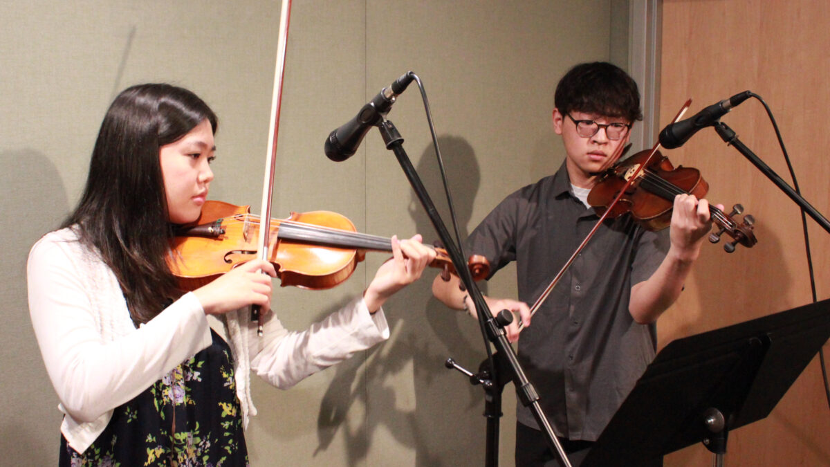 two teens performing on violin