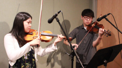 two teens performing on violin