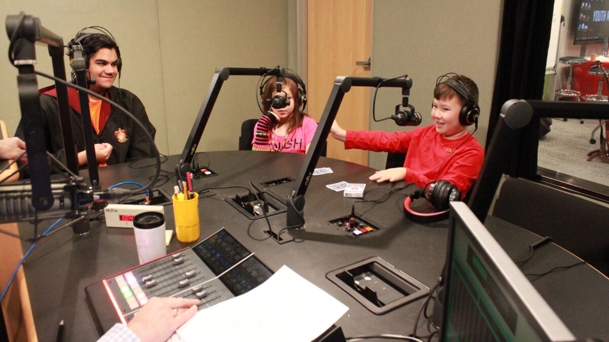 Society-of-American-Magicians-Youth-3 Three youth wearing headphones speaking into microphones in a radio studio