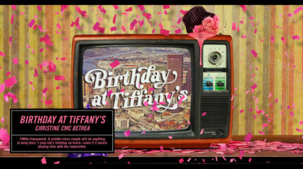 A cupcake laying face down on a old school television depicting a backdrop of a city and the text "Birthday at Tiffany's" in white cursive font in front of a striped green background , with pink confetti dropping down