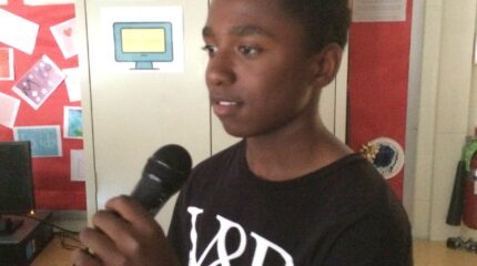 A youth holding and speaking into a microphone