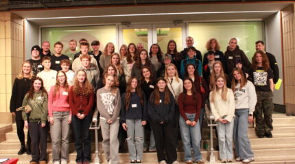 Forty one teens and one adult smiling while standing on a staircase