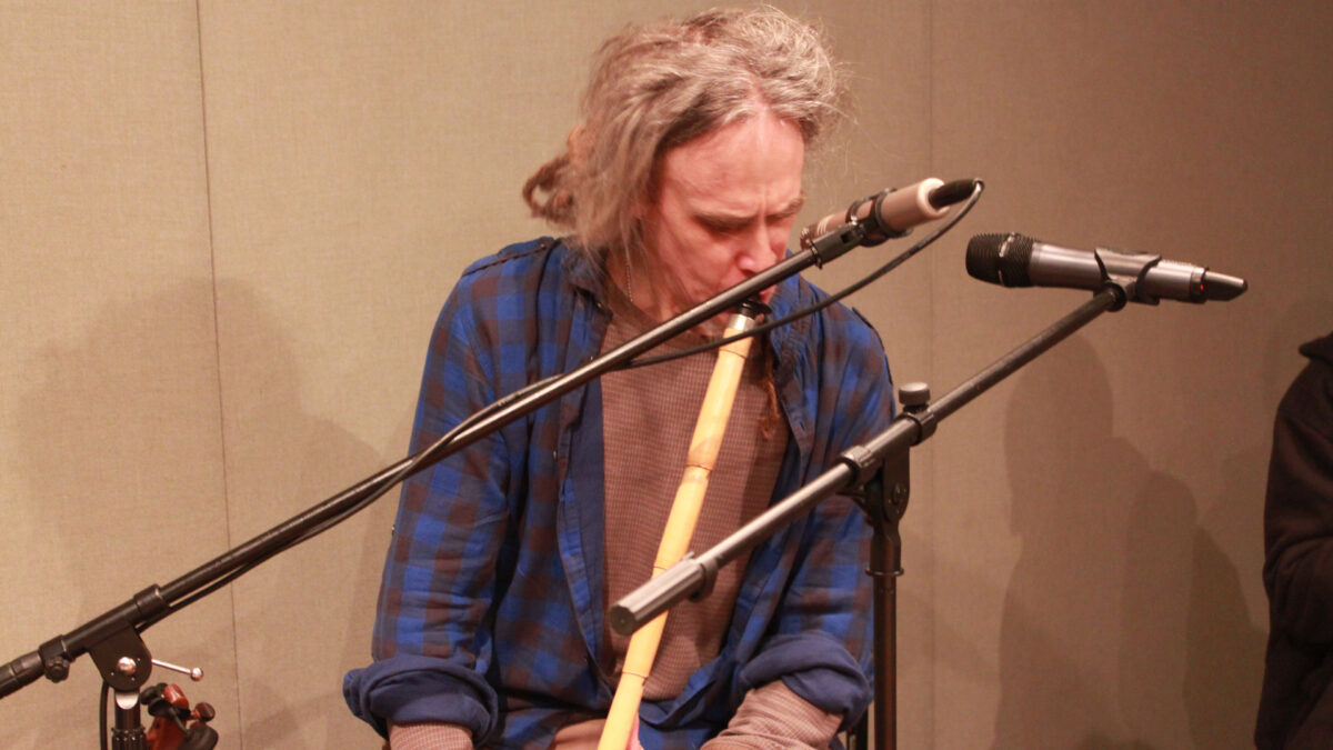 An adult playing an ethnic wind instrument in a radio studio