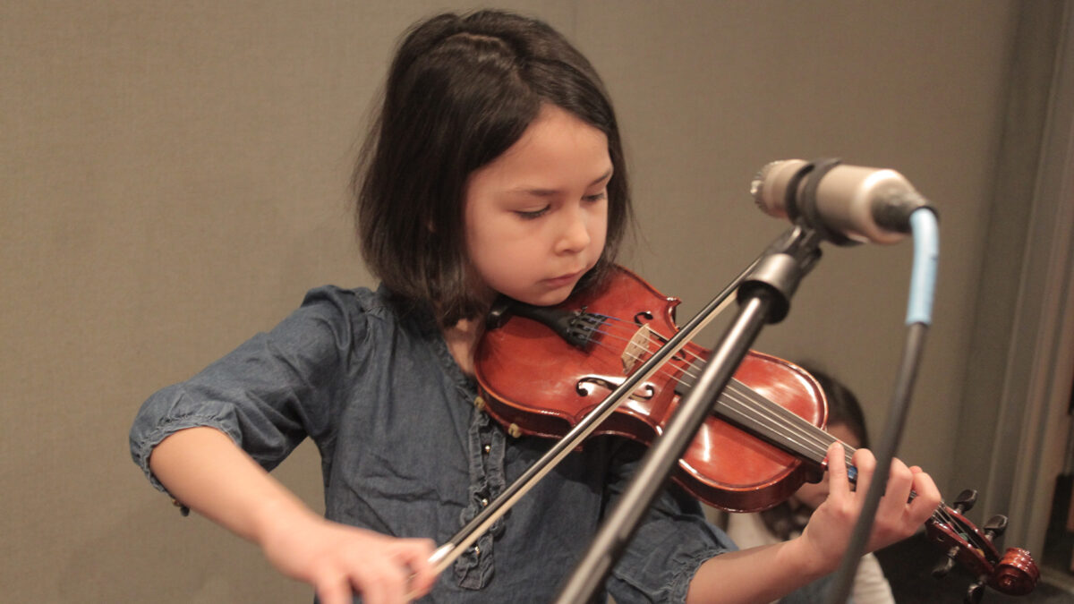 A youth playing violin in a radio studio