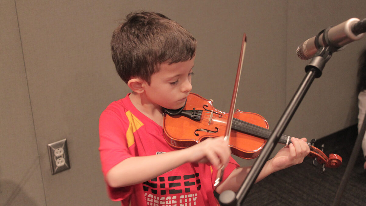 A youth playing violin in a radio studio