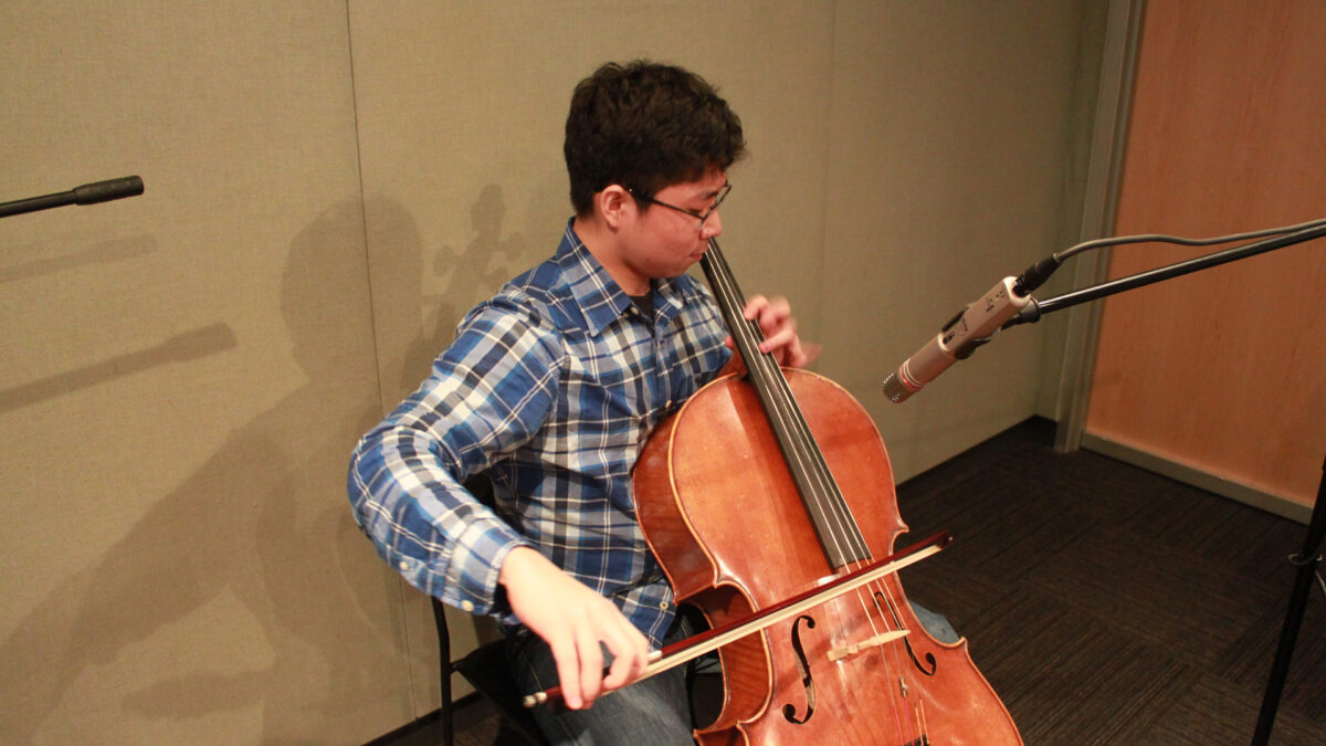 A youth playing a cello in a radio studio