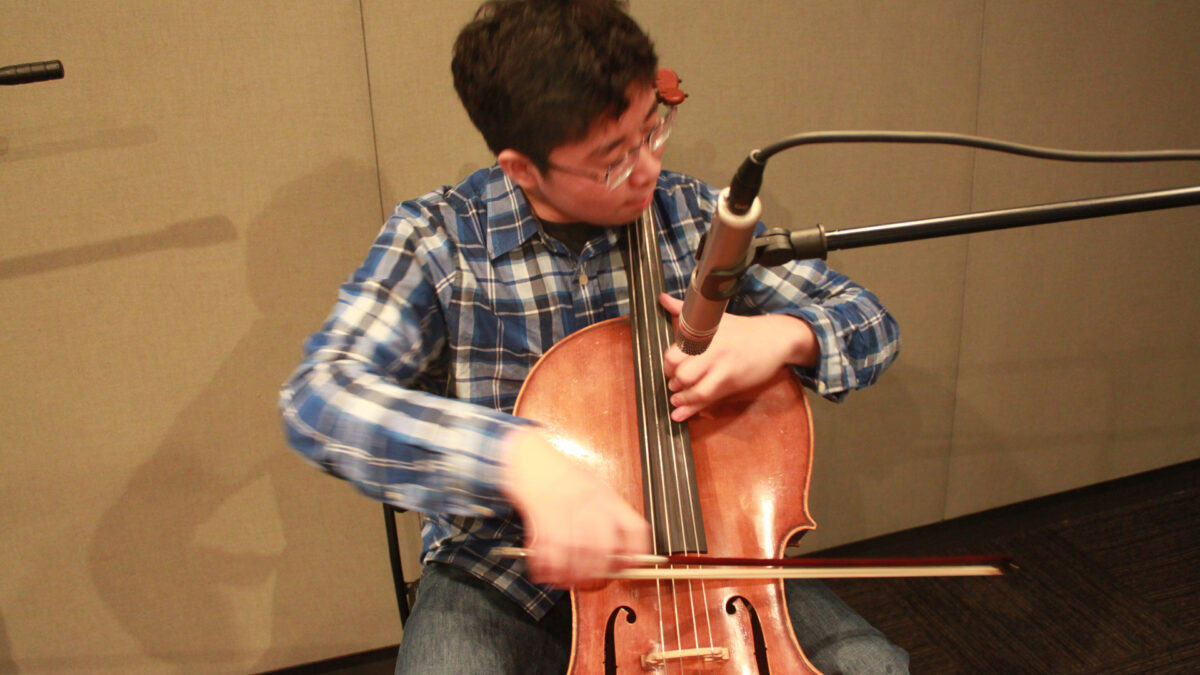 A youth playing a cello in a radio studio
