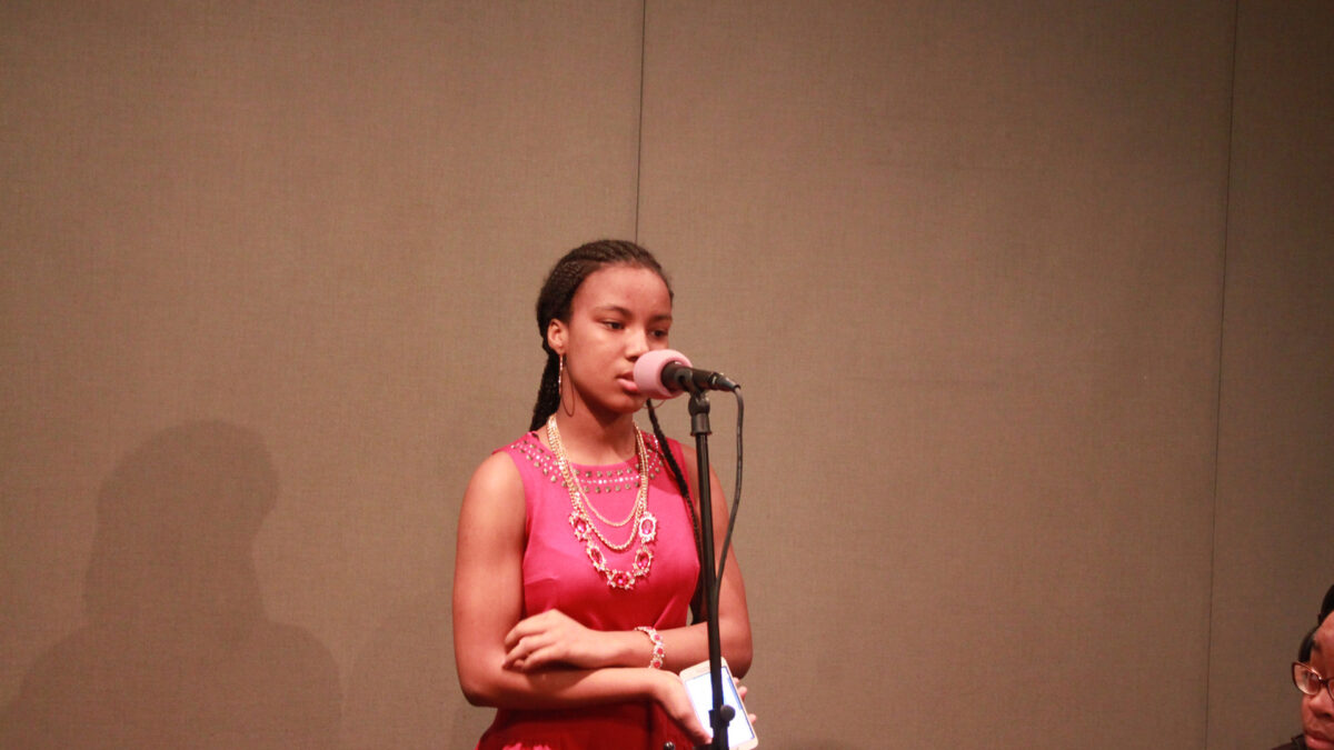 A youth holding a cell phone and speaking into a microphone in a radio studio