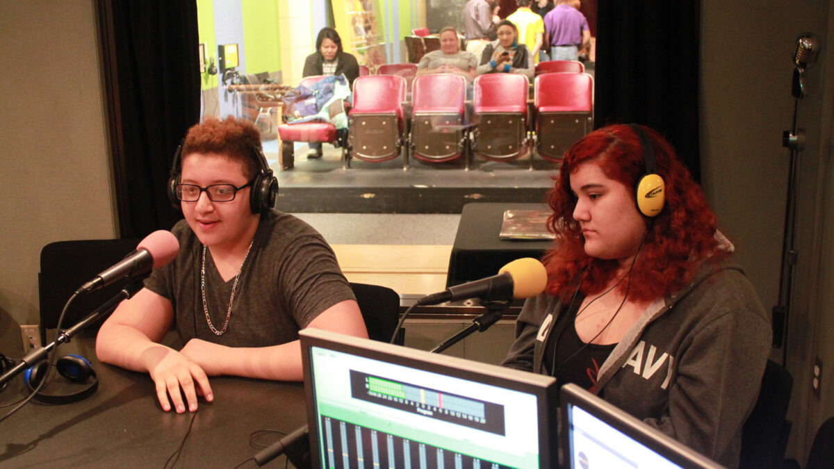 IMG_8025_wp Two teens wearing headphones speaking into microphones in a radio studio