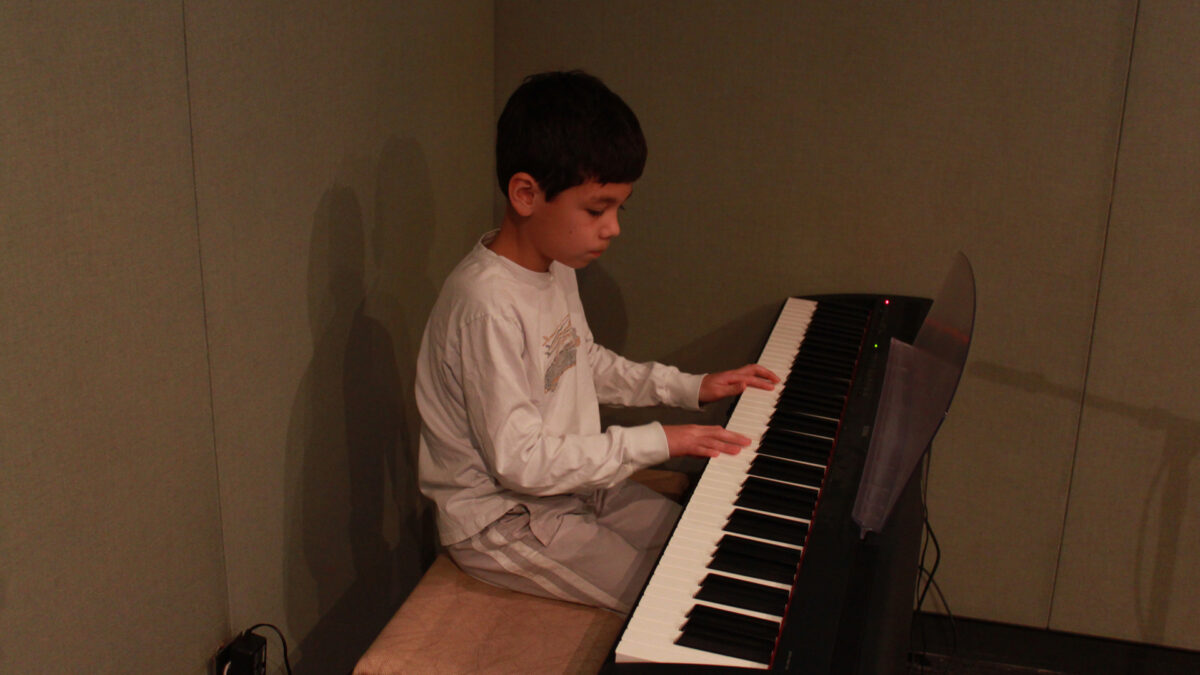 A youth playing a piano keyboard in a radio studio