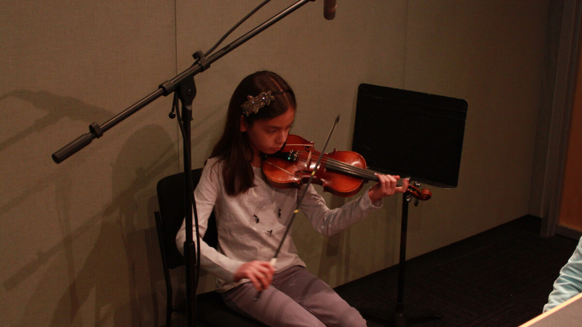 A youth playing a violin in a radio studio