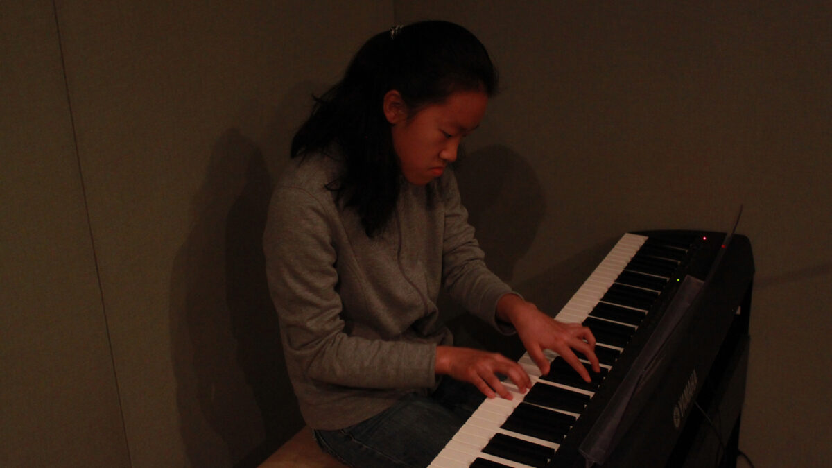 A youth playing piano keyboard in a radio studio