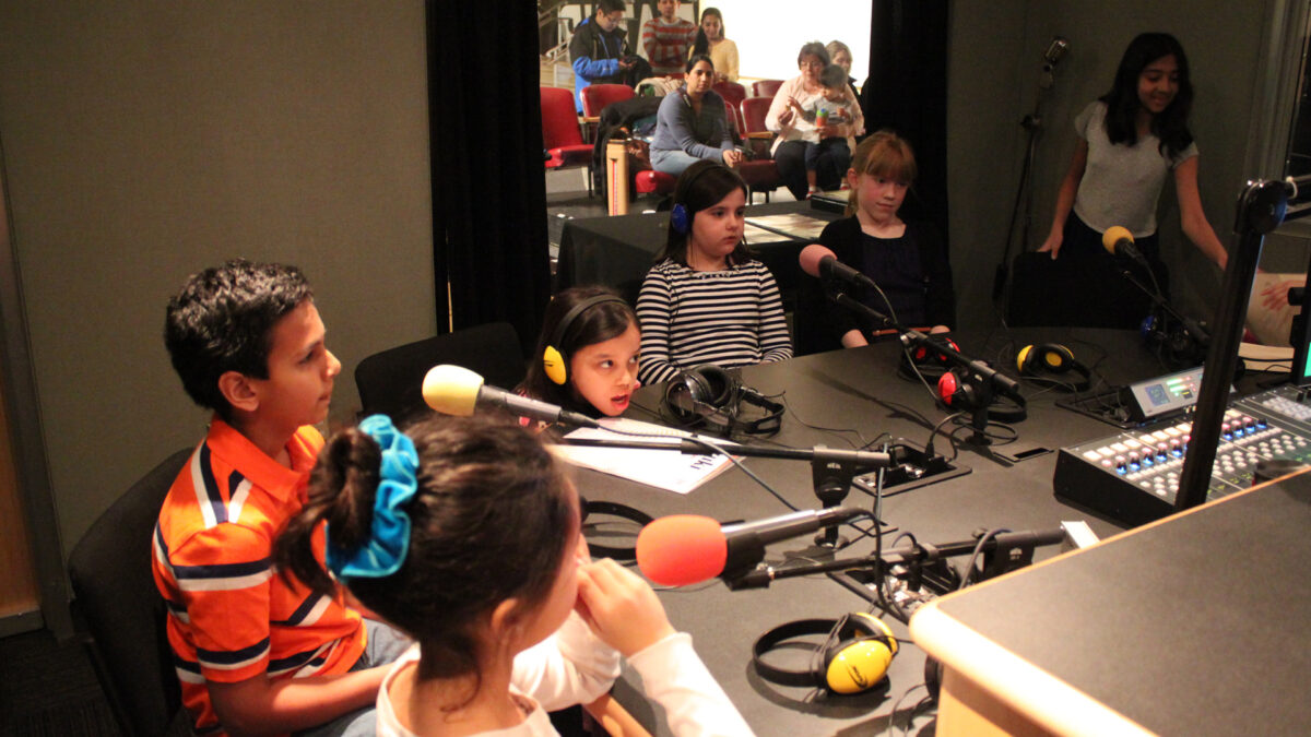 IMG_8447_wp Six youth, two wearing headphones, speaking into microphones in a radio studio