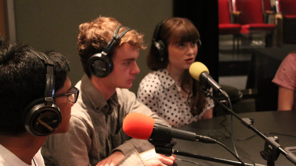 IMG_8526 Three teens wearing headphones speaking into microphones in a radio studio