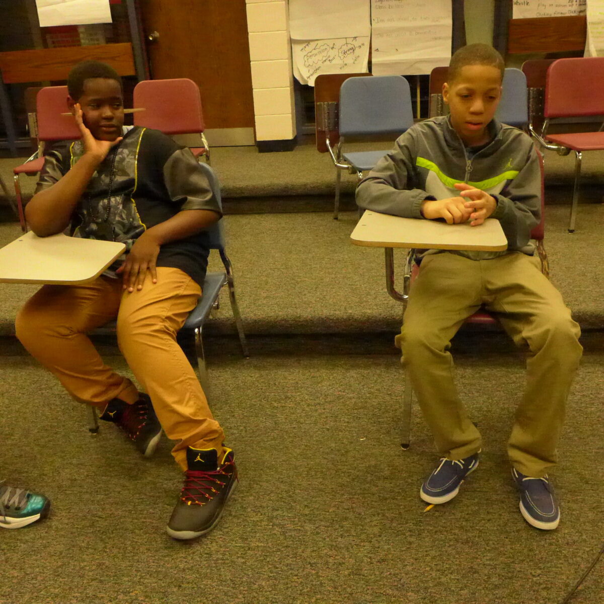 Two youth sitting on classroom chairs