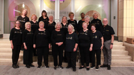 Seventeen adults smiling and posing in profile on a staircase