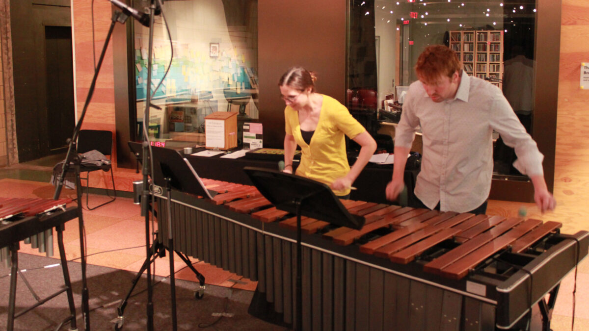 Two adults playing a marimba standing behind music stands
