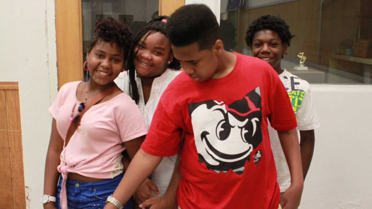Four youth smiling and posing in a classroom
