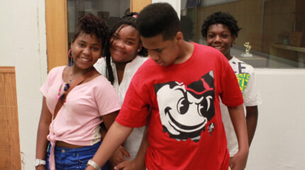 Four youth smiling and posing in a classroom