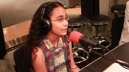 A youth wearing headphones speaking into a microphone in a radio studio