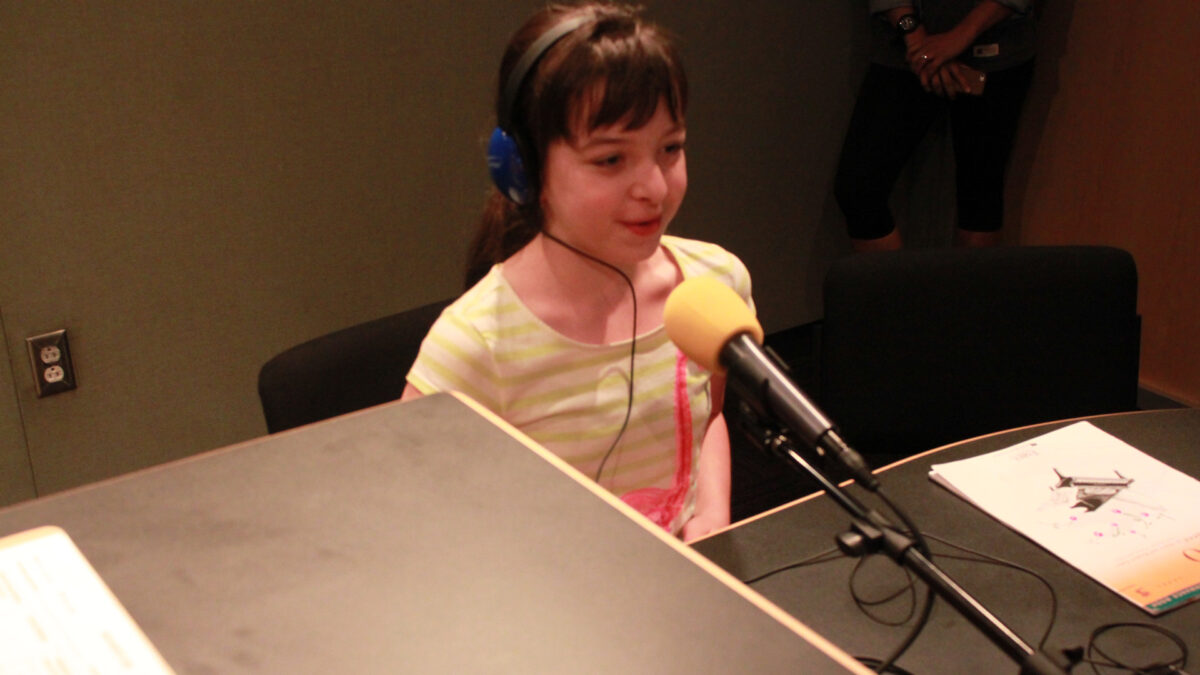 A youth wearing headphones speaking into a microphone in a radio studio