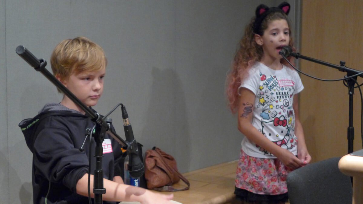 A youth playing a drum into a microphone and a youth singing into a microphone in a radio studio.
